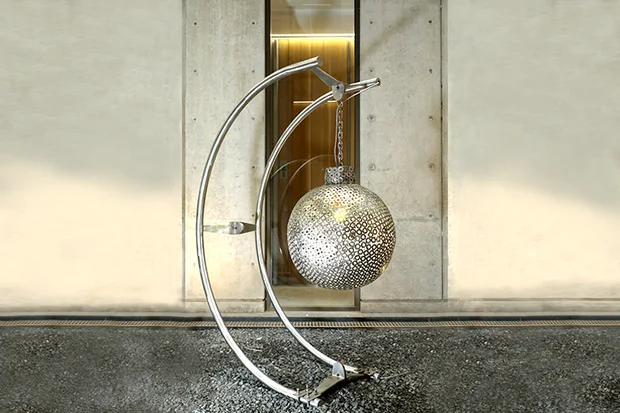 Perforated steel sphere hung from an arc